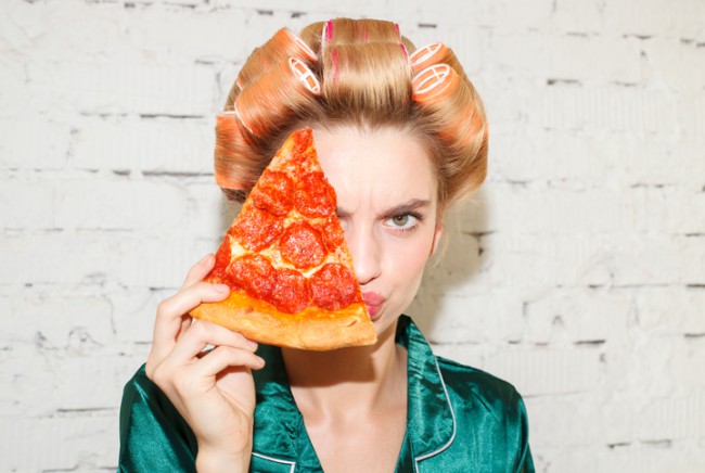 femeie care tine in dreptul fetei o felie de pizza