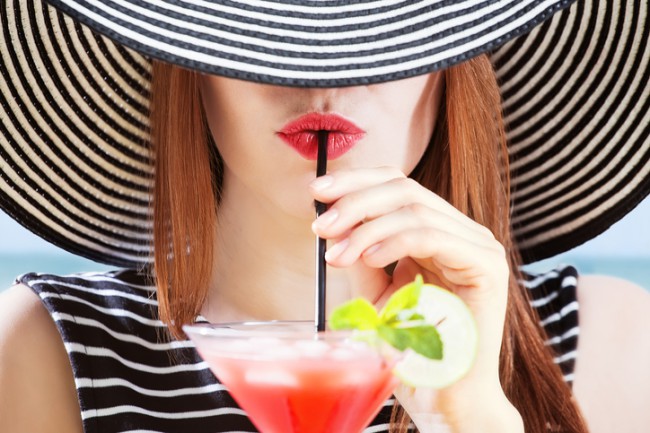 femeie cu palarie care bea dintr-un cocktail