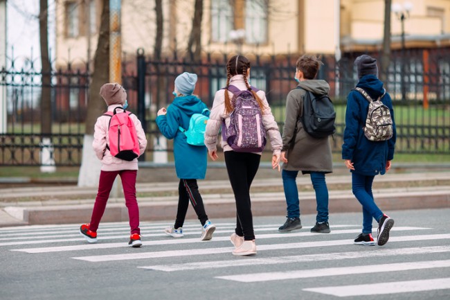 elevi cu ghiozdanele in spate care se duc la scoala