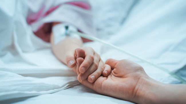 mainile a doua femei pe un pat de spital