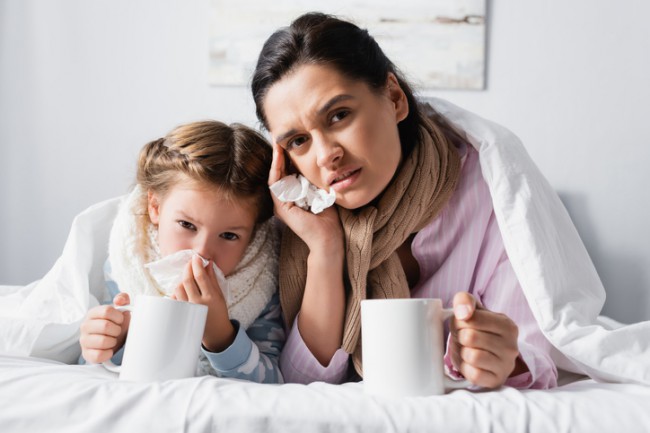 mama si fiica in pat cu cate o cana alba in fata