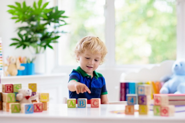 copil care se joaca cu cuburi cu litere