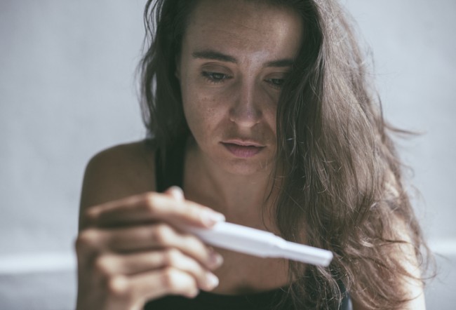 femeie suparata care se uita la un test de sarcina