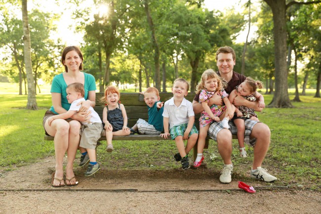parinti cu 9 copii pe o banca in parc