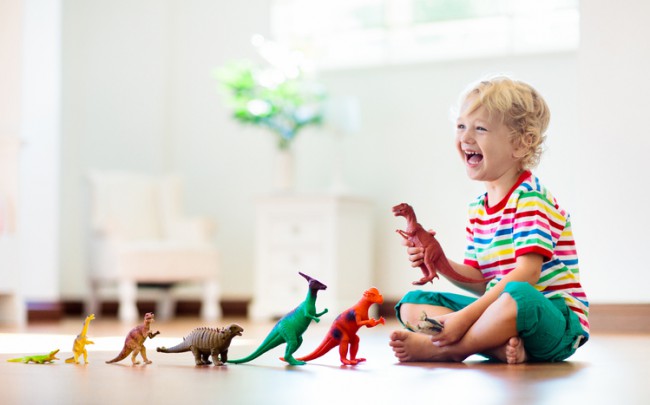 copil care se joaca cu figurine sub forma de dinozauri