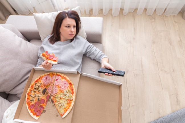 femeie care mananca pizza pe canapea
