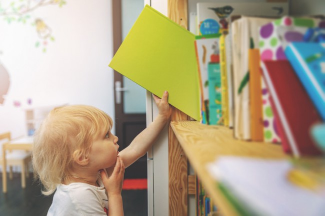 copil care ia o carte din biblioteca