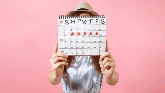 femeie care tine in mana un calendar de ovulatie