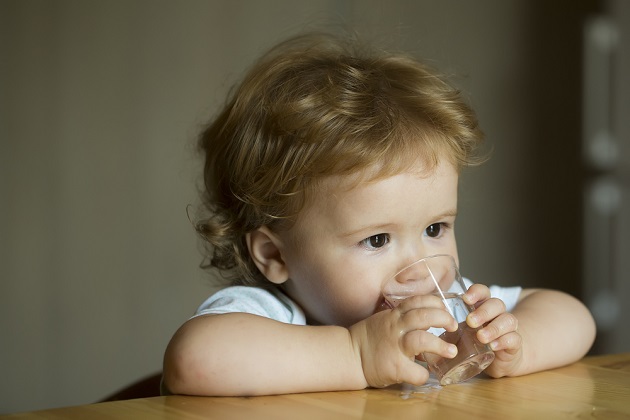 copil care bea apa dintr-un pahar