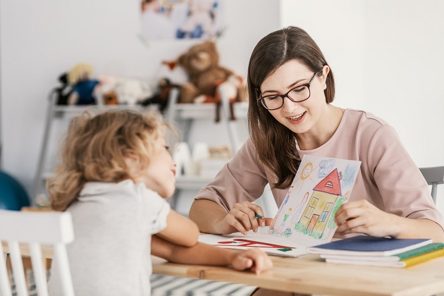 femeie care ii arata unei fetite un desen cu o casa