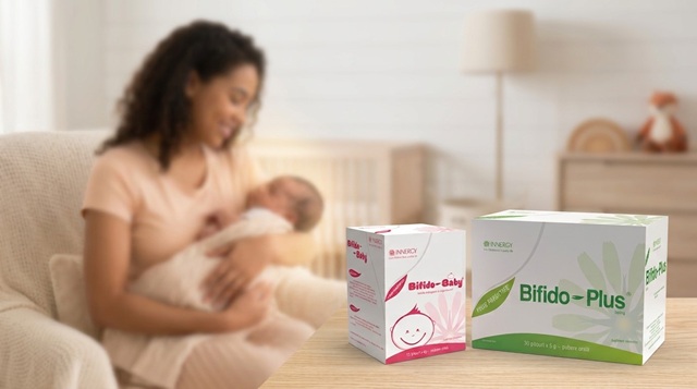 mama care tine in brate un bebelus in fundal