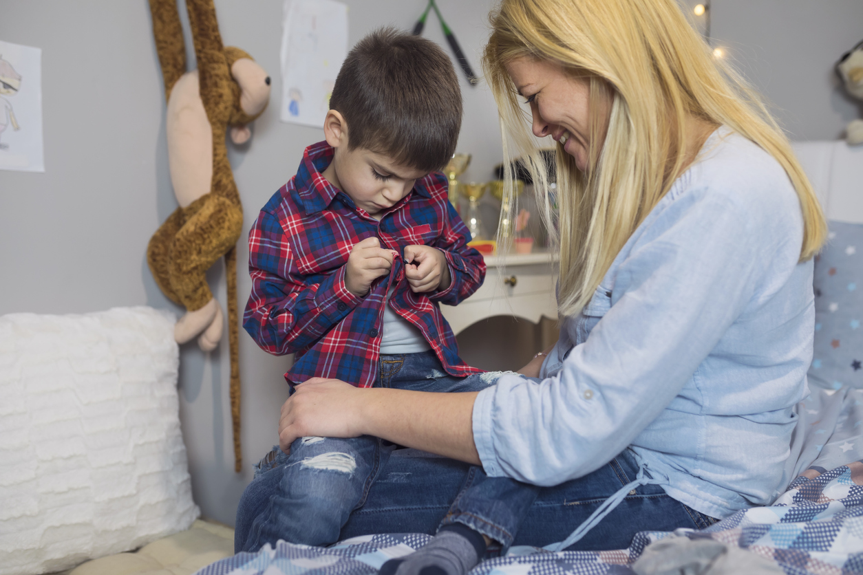 baietel care se incheie singur la camasa asistat de mama sa