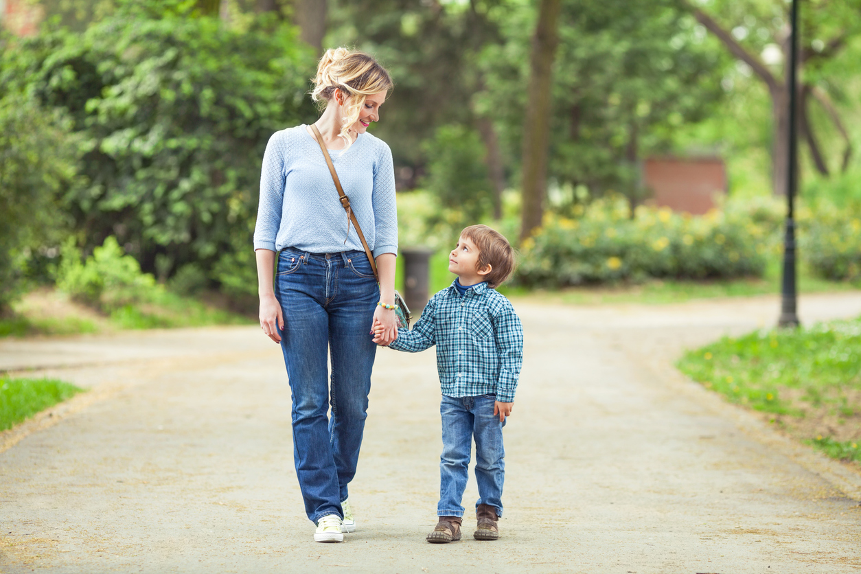 mama care isi tine copilul de mana in parc