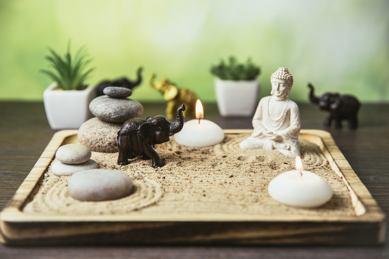 o tava cu obiecte feng shui: elefant, statuie buddha, nisip, lumânari, pietre