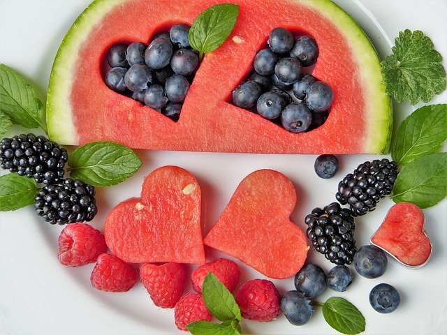 imagine cu multe fructe decupate si asezate in forma de inima: mure, pepene, afine, fragi