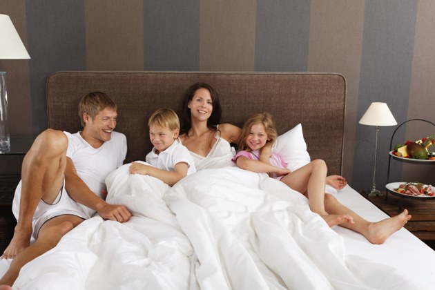familie cu copii asezata in pat
