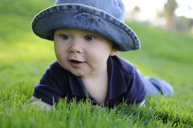 bebelus stand pe burta in iarba