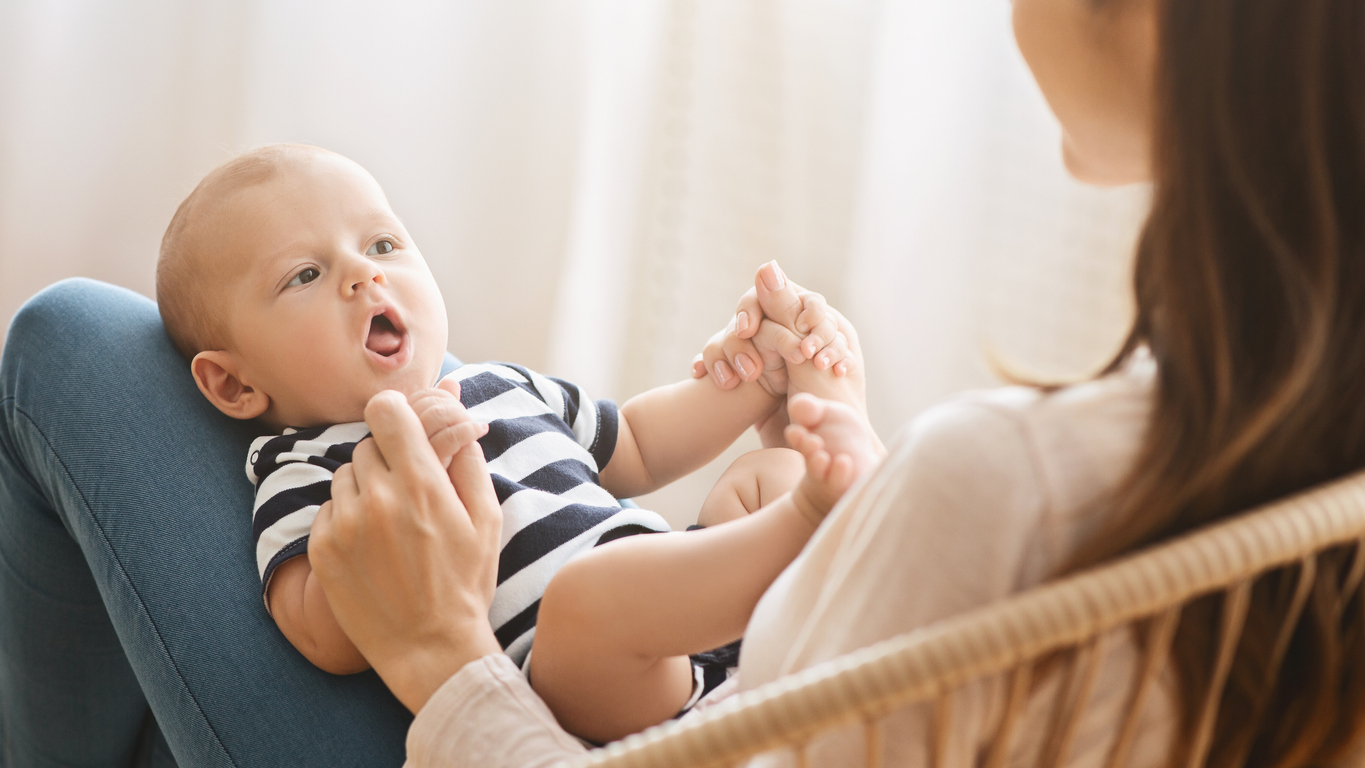 ujn bebelus care sta pe picioarele mamei si incearca sa vorbeasca