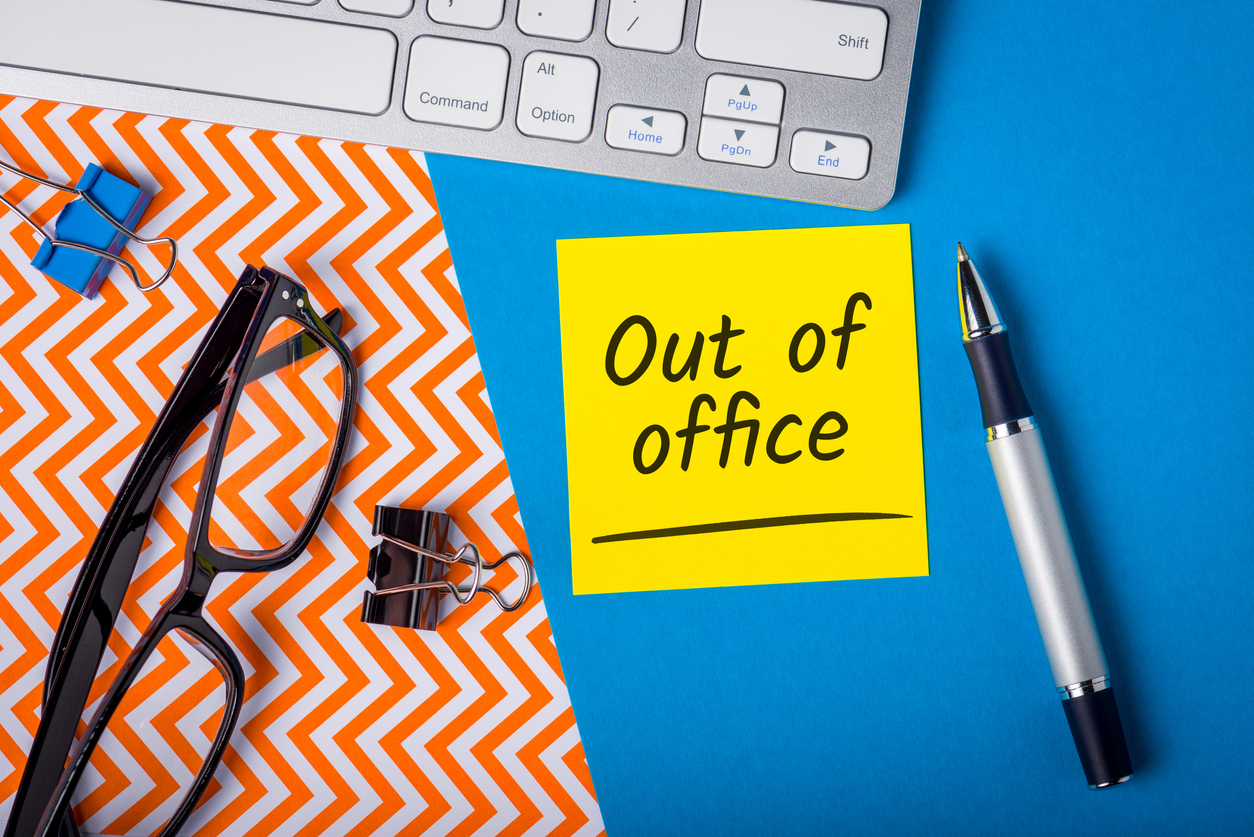 birou cu diferite accesorii si cu un mesaj pe care scrie out of office