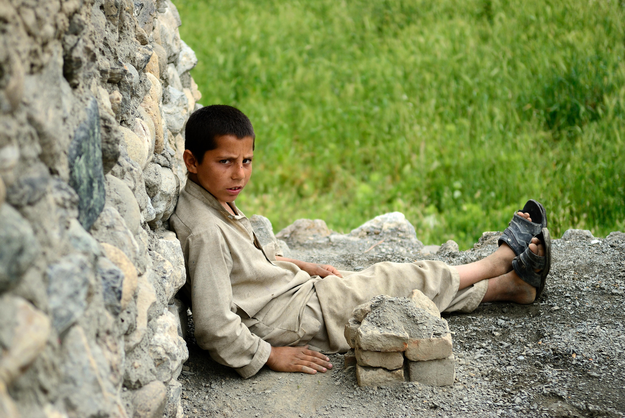 copil afgan stand jos in praf rezemat de un perete