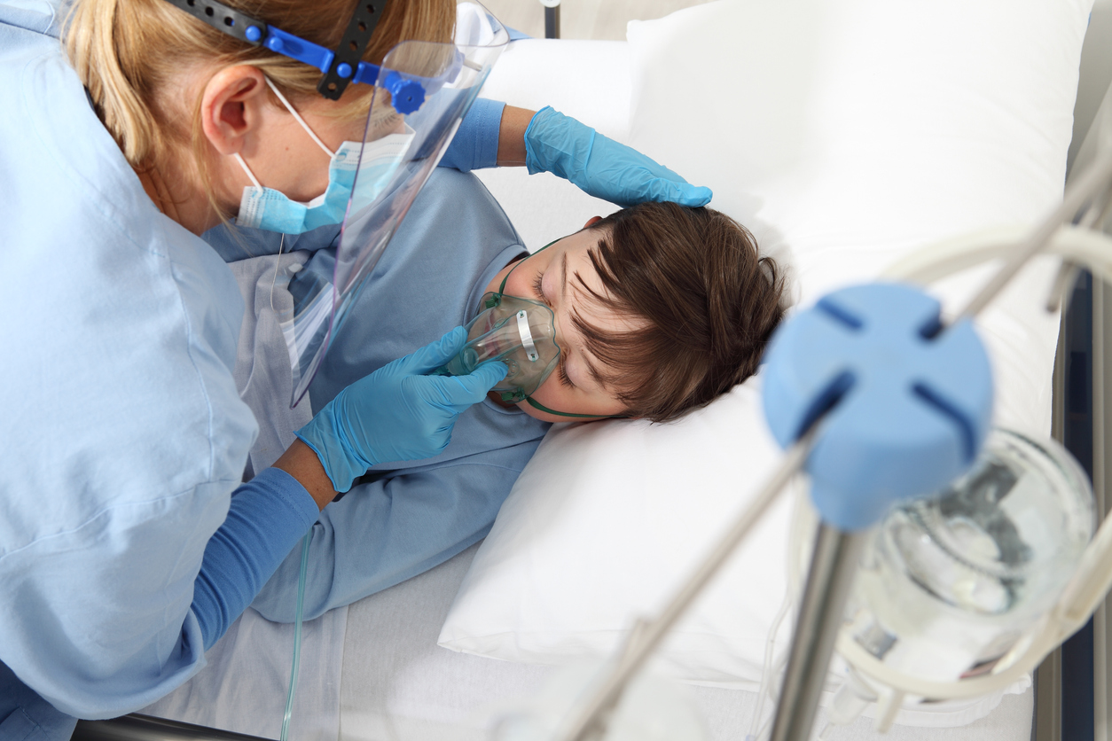 copil in pat de spital cu masca de oxigen