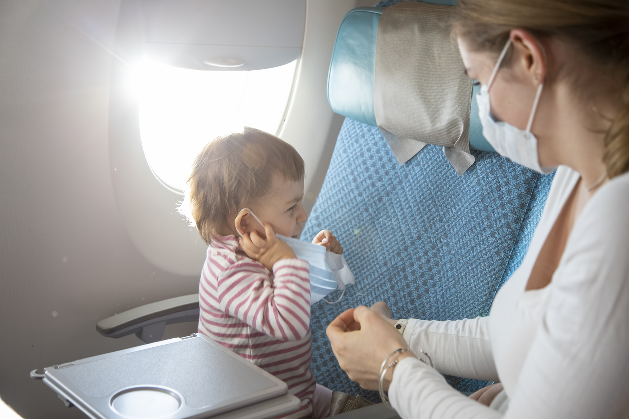mama cu bebelus stan din scaune in avion purtand masca