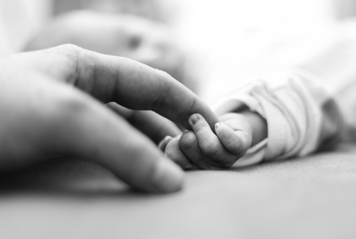 prim plan cu mana unei mame tinand de mana unui bebelus