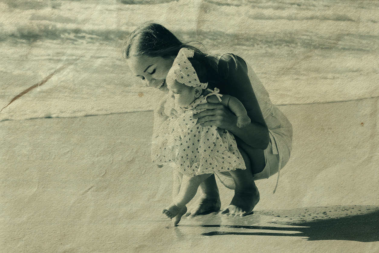 fotografie veche cu o mama si bebelusul ei pe plaja