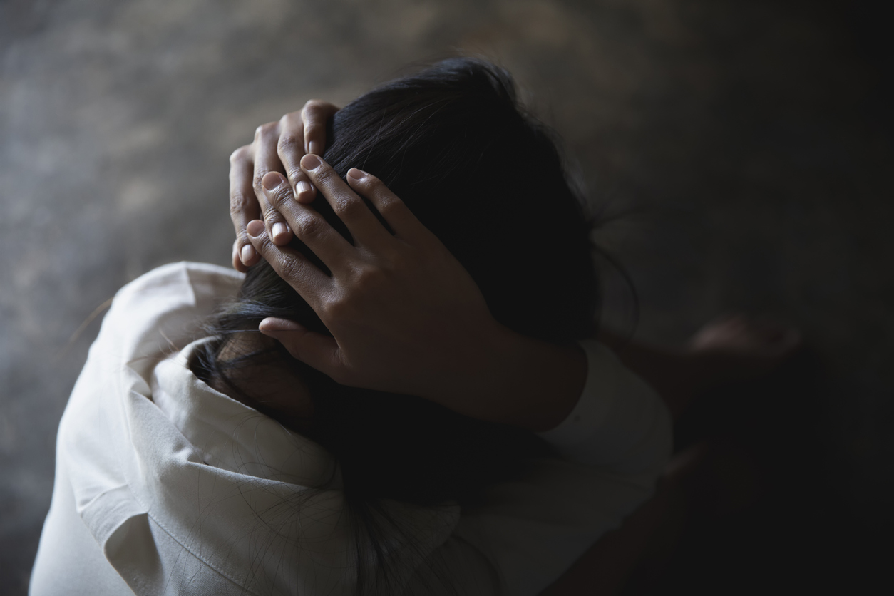 femeie abuzata stand ghemuita cu mainile pe cap