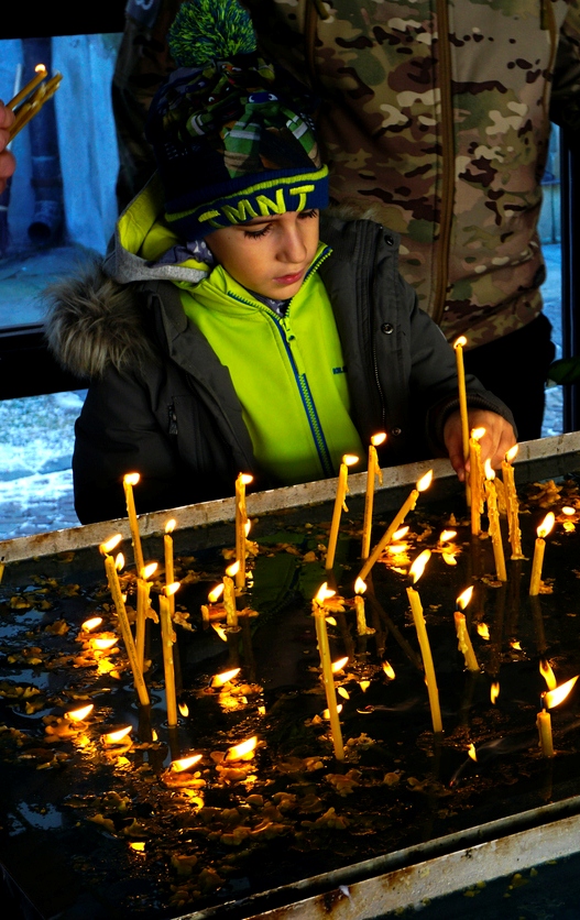 baietel aprinzand lumanare la biserica