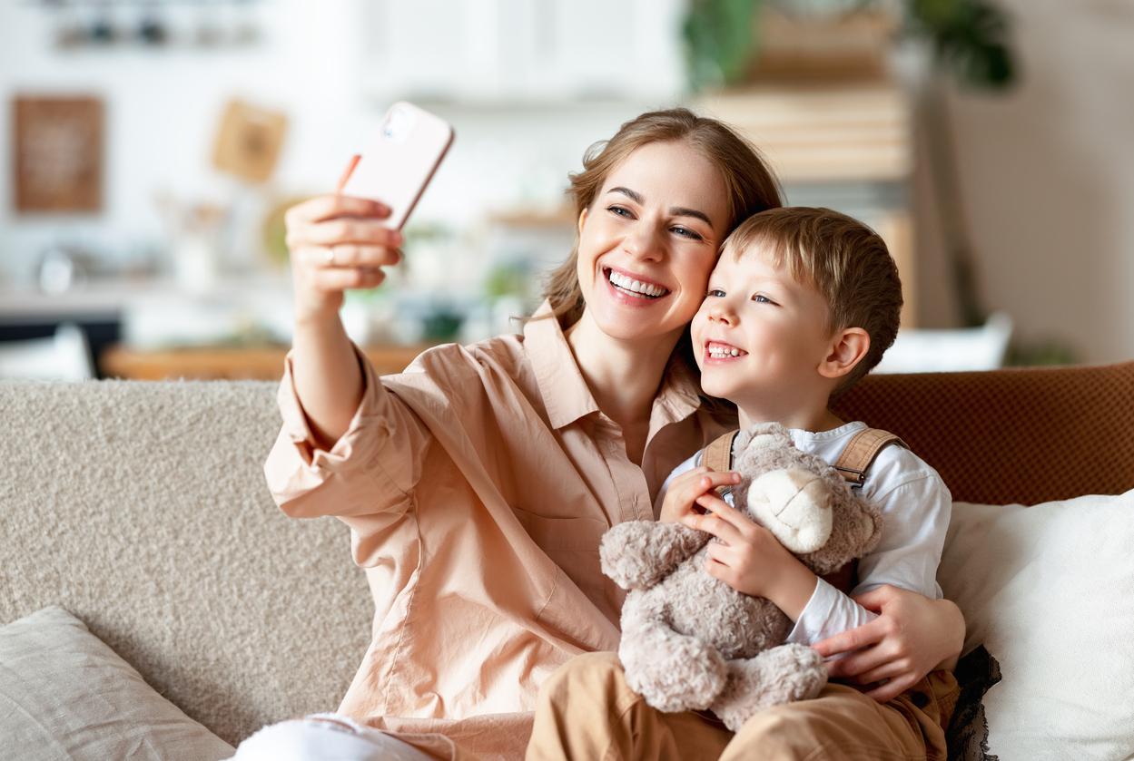 mama si fiul ei facand un selfie impreuna pe canapea in casa