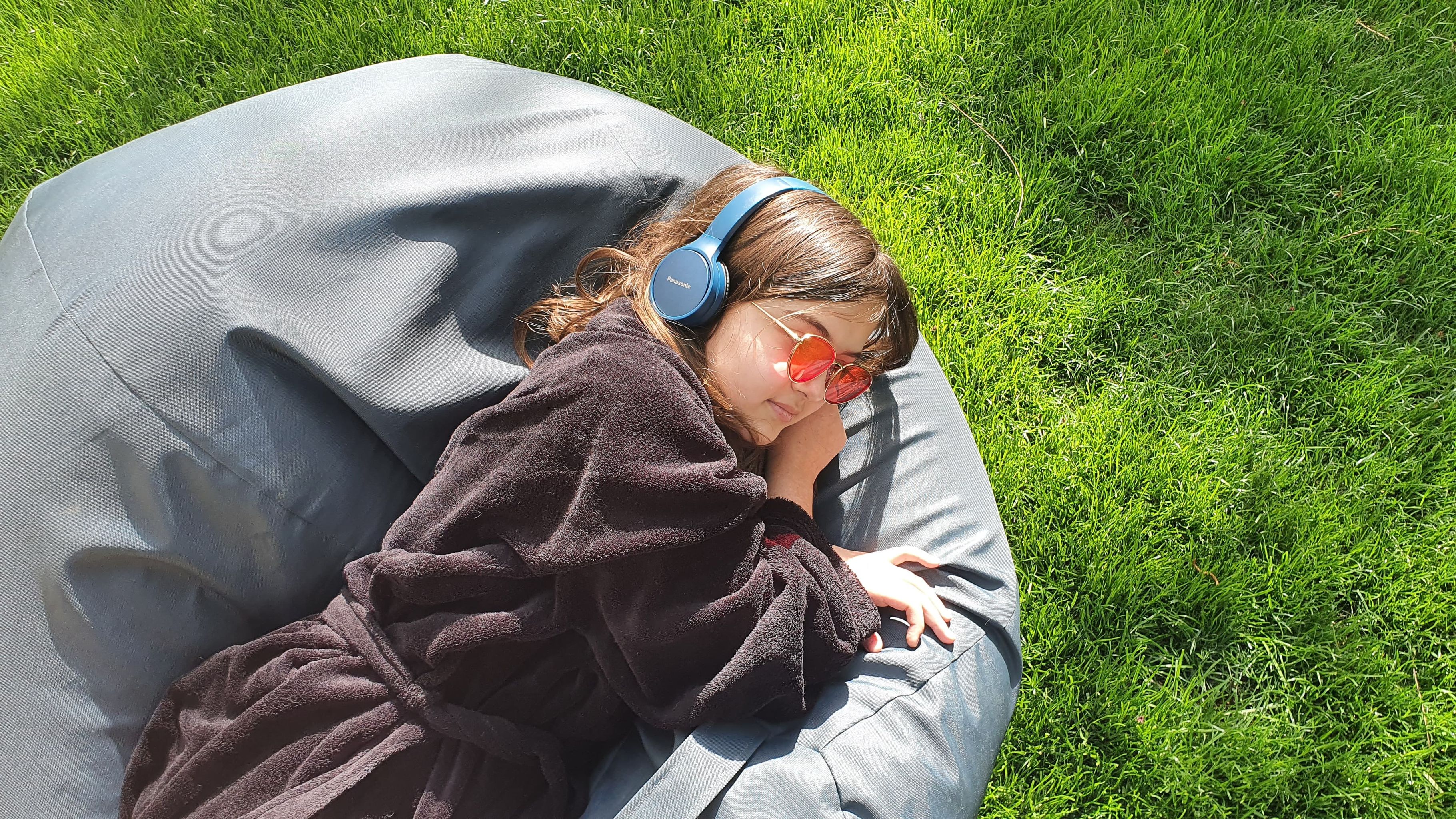 adolescenta ascultand muzica in iarba asezata pe un fotoliu puf