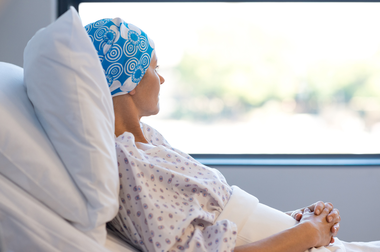 femeie bolnava de cancer stand in pat si uitandu-se pe geam