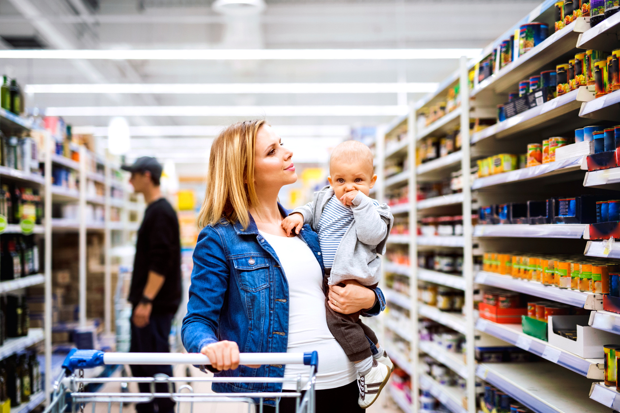 o femeie tinand un bebelus in brate intr-un supermarket