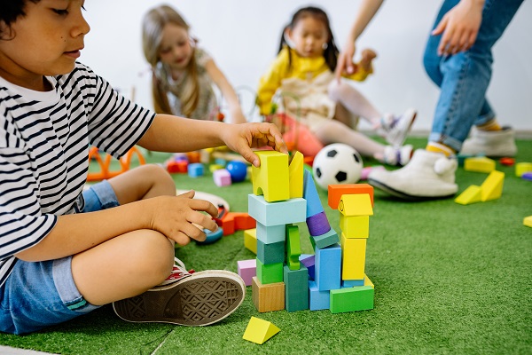 Copil care se joaca cu niste cuburi colorate de lemn
