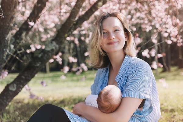 mama isi tine bebelusul in brate in parc