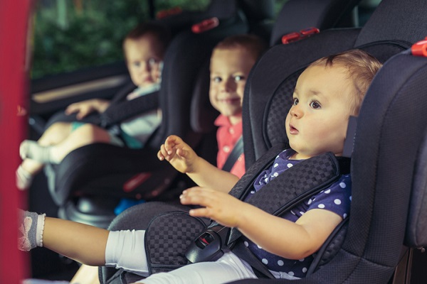 trei bebelusi in scaune auto in masina