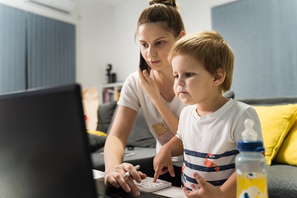 mama vorbeste la telefon si cauta pe laptop cu baiatul langa ea