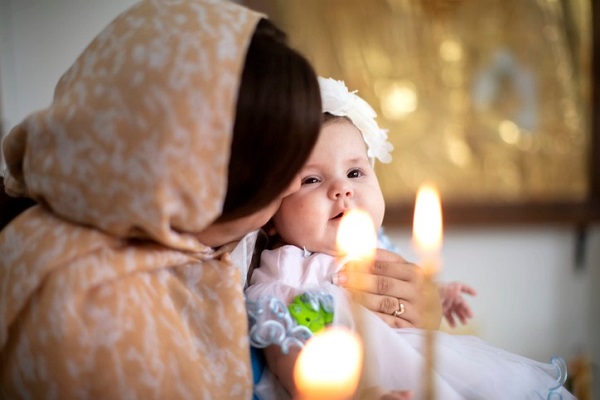 mama isi tine fetita in brate la biserica