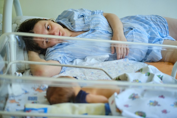 femeie in salon la maternitate sta intinsa langa bebelus