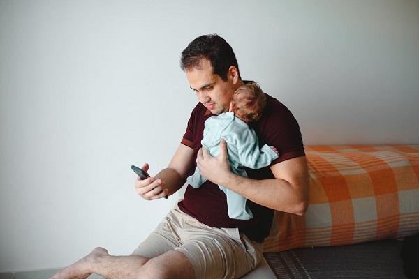tata cu bebelus in brate sta pe telefon