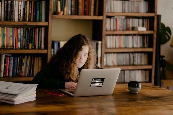 fata se uita pe laptop la biblioteca