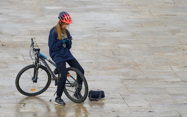 fata pe bicicleta se uita pe telefon