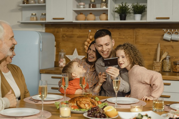 familie mama tata copii bunici stau la masa tata pe telefon