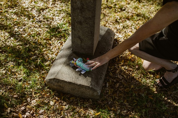o femeie lasa o jucarie albastra la o cruce in cimitir