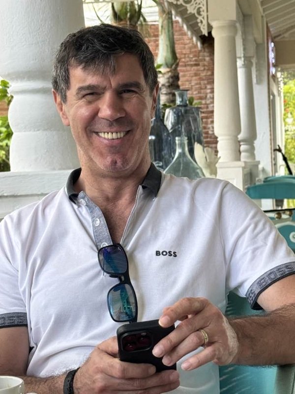 mihai leu in tricou alb cu telefonul in mana zambeste