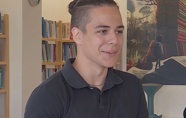 baiat in tricou negru cu o coada neagra prinsa in crestetul capului da interviu