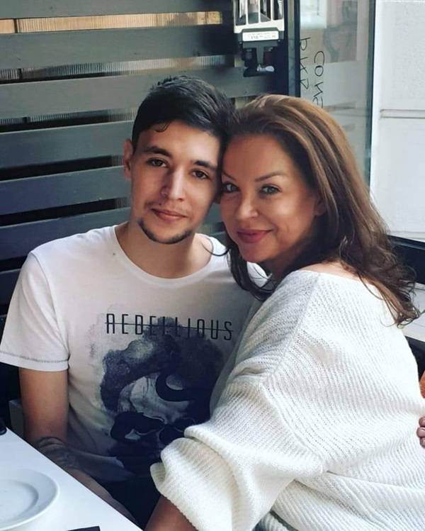 eugenia serban cu parul lung saten imbracata in alb isi tine fiul in brate