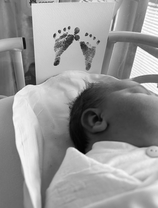 poza alb negru cu un nou nascut pe patul de spital