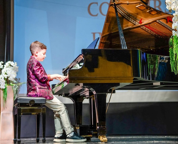 luca uzun imbracat in sacou mov canta la pian